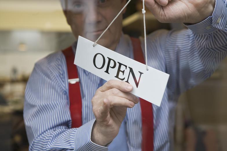 business owner turning sign to "open"